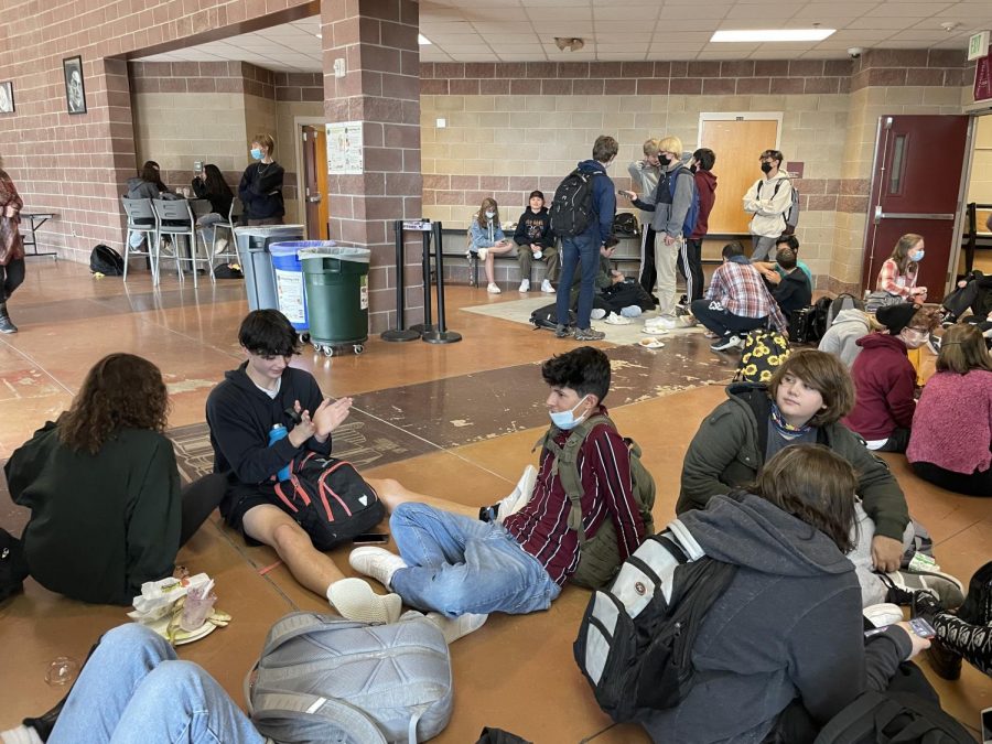 Students gather around at lunch taking a break to eat and hang out with friends.  They are deciding on how they want to dispose of their food. Are they are going to leave it for others to pick up, or throw it in the correct bins?