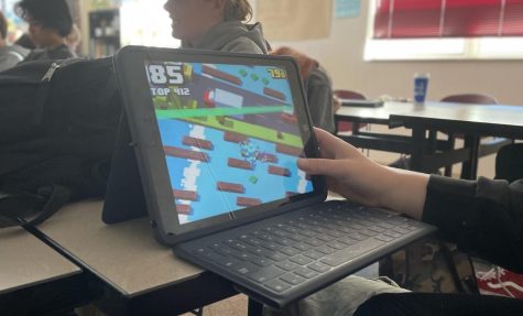 During work time in class, a student plays a game on their iPad instead of doing their work. This is one reason why the school has had to reinforce rules.
