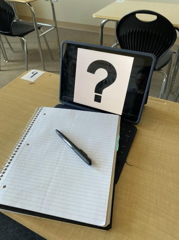 Laying on an IPad, a notebook and pen wonder if they will soon become unnecessary or they will prevail in the battle between the two types of learning. It is a mystery, hence the question mark.