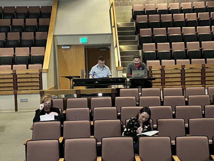 Tracy Knick, Rhett North, Kendle Butterworth, and William Legg sit in the audience of the Silver Creek theatre, taking notes on students auditioning for the spring musical.