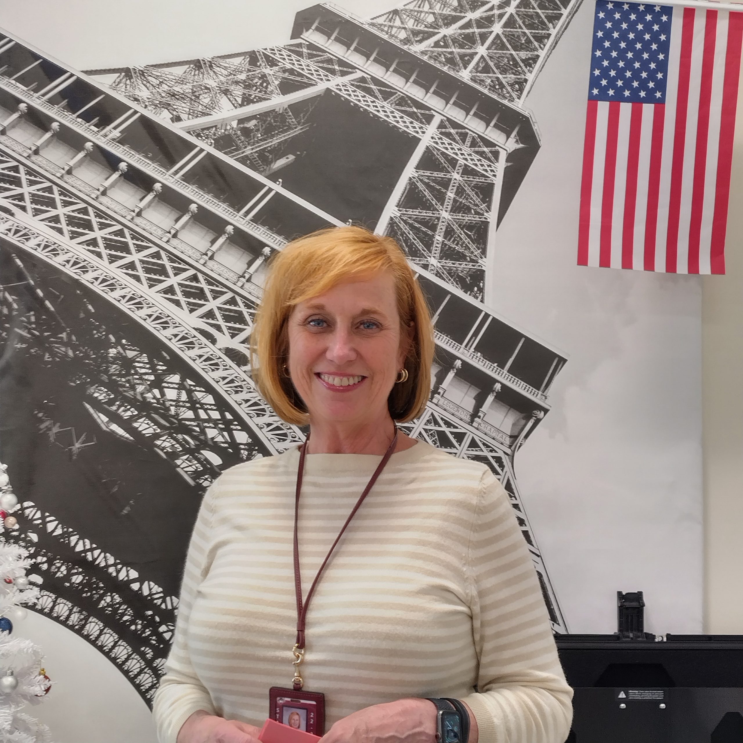 Mrs Knick standing with pride in front of an Eiffel Tower painting in the french clubs room.