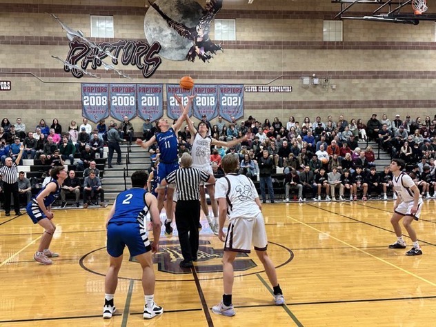 Junior Zander Storz fights for the jump ball to kick off the rivalry game against the Longmont Trojans.