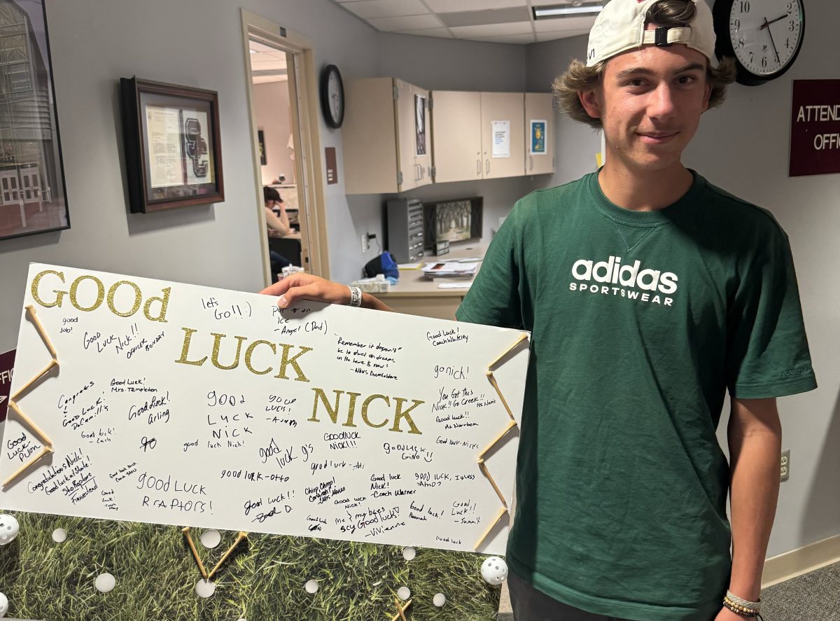 Nick+Horvath+holding+sign+made+by+Silver+Creek+staff+to+wish+him+good+luck+at+state+golf+tournament.