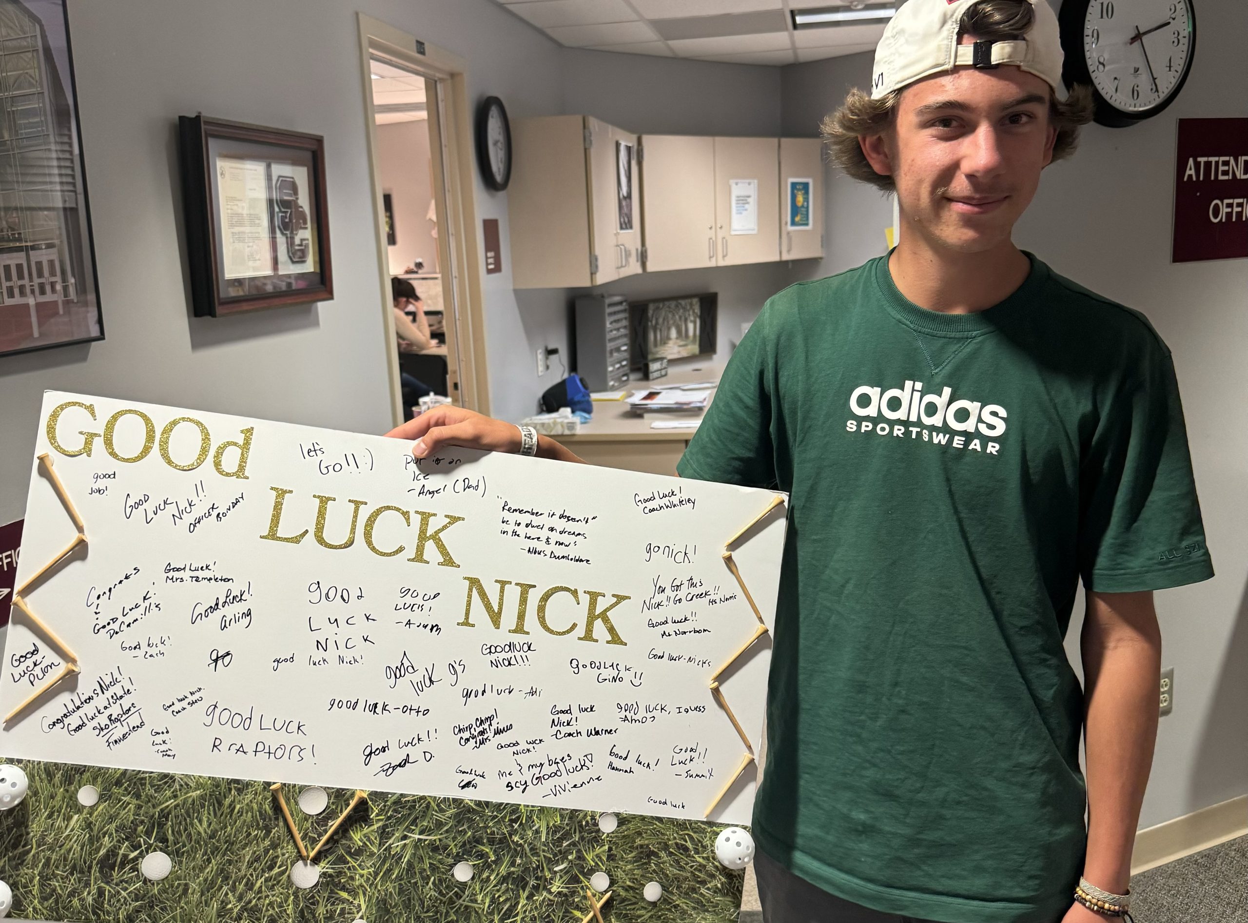 Nick Horvath holding sign made by Silver Creek staff to wish him good luck at state golf tournament.