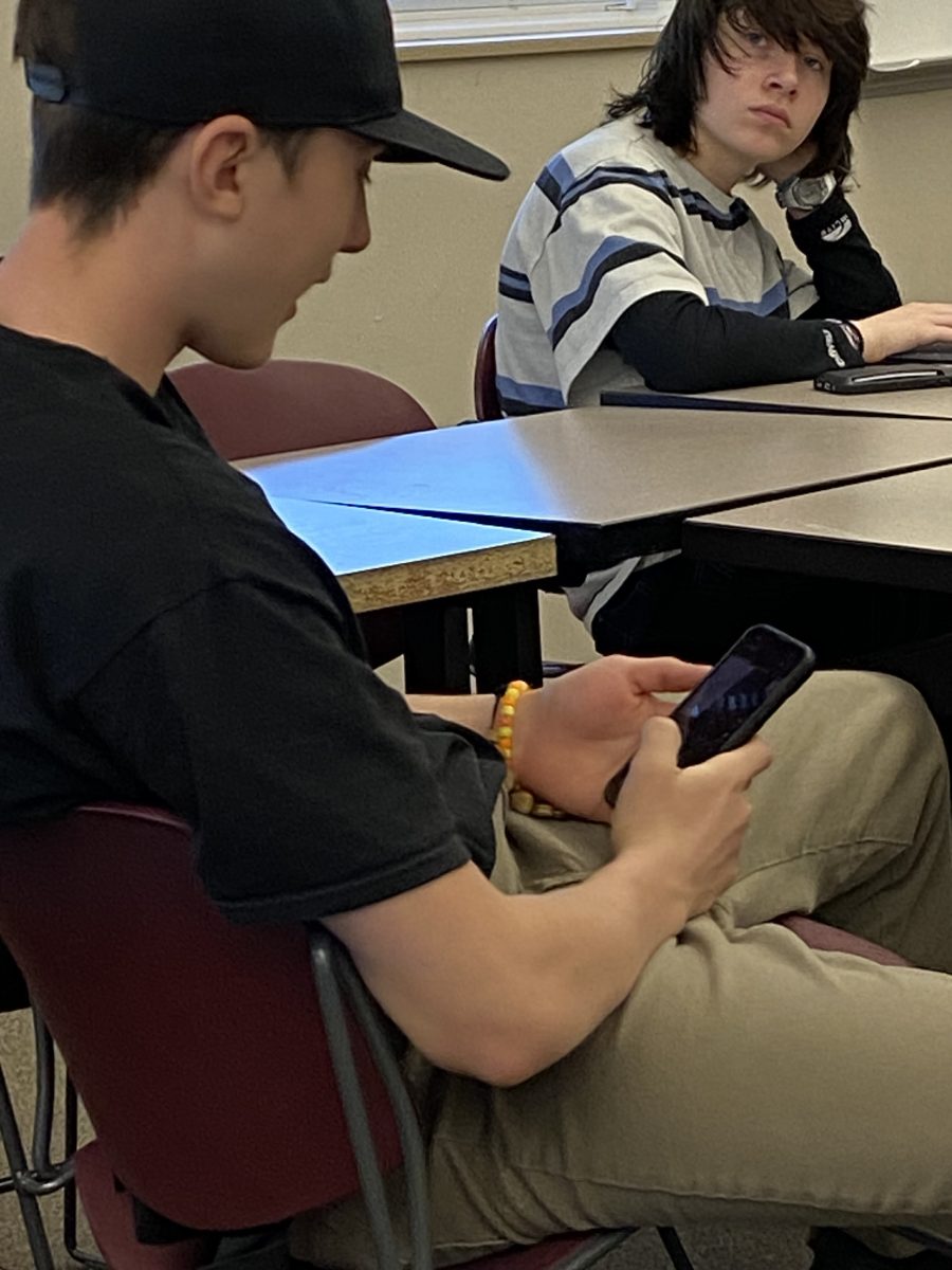 Tristan Herrera using his iPhone during class, Kein Peterson in the background.