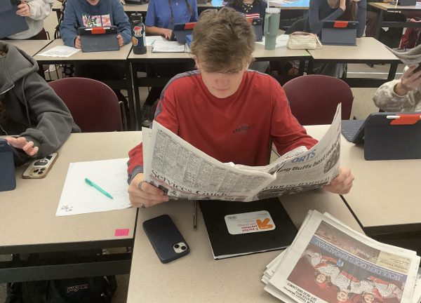 Seth Davis reads the newspaper during journalism class to learn more about writing articles.