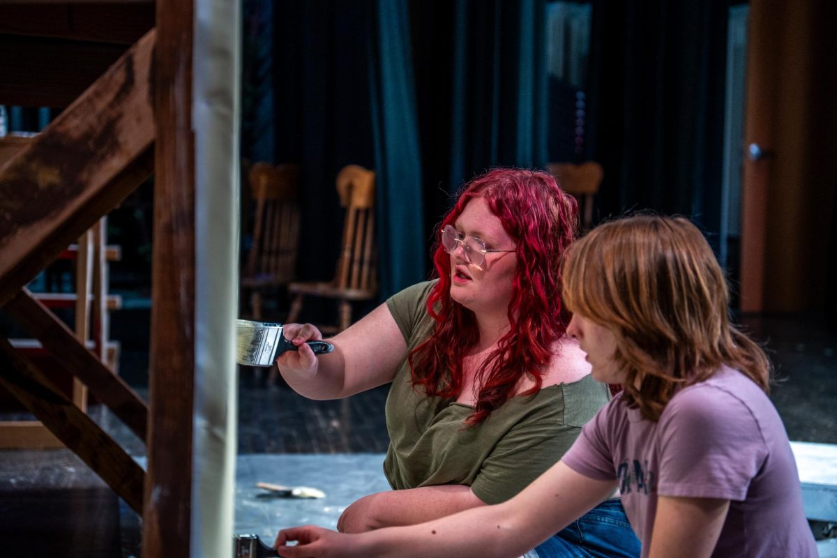 Two students painting a set peace.